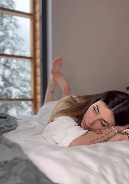 Michelle Comi, modella di OnlyFans, foto sdraiata a letto con un accappatoio.