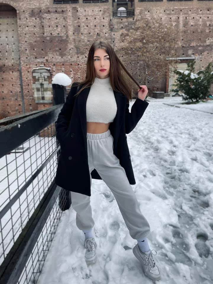 Elisa Esposito @eli.esposito foto della modella di OnlyFans in piedi sulla neve con un top e pantaloni grigi aderenti