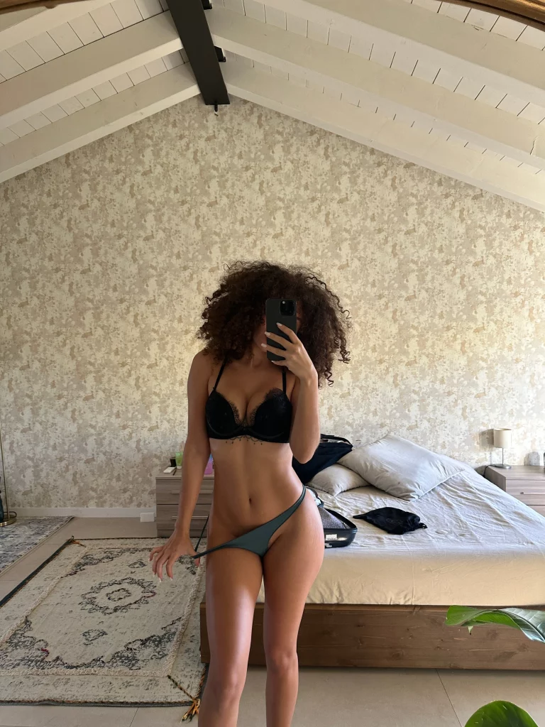 Beatrice Segreti @beasecrets immagine di modello OnlyFans in camera da letto che indossa un reggiseno nero e sta togliendo il perizoma