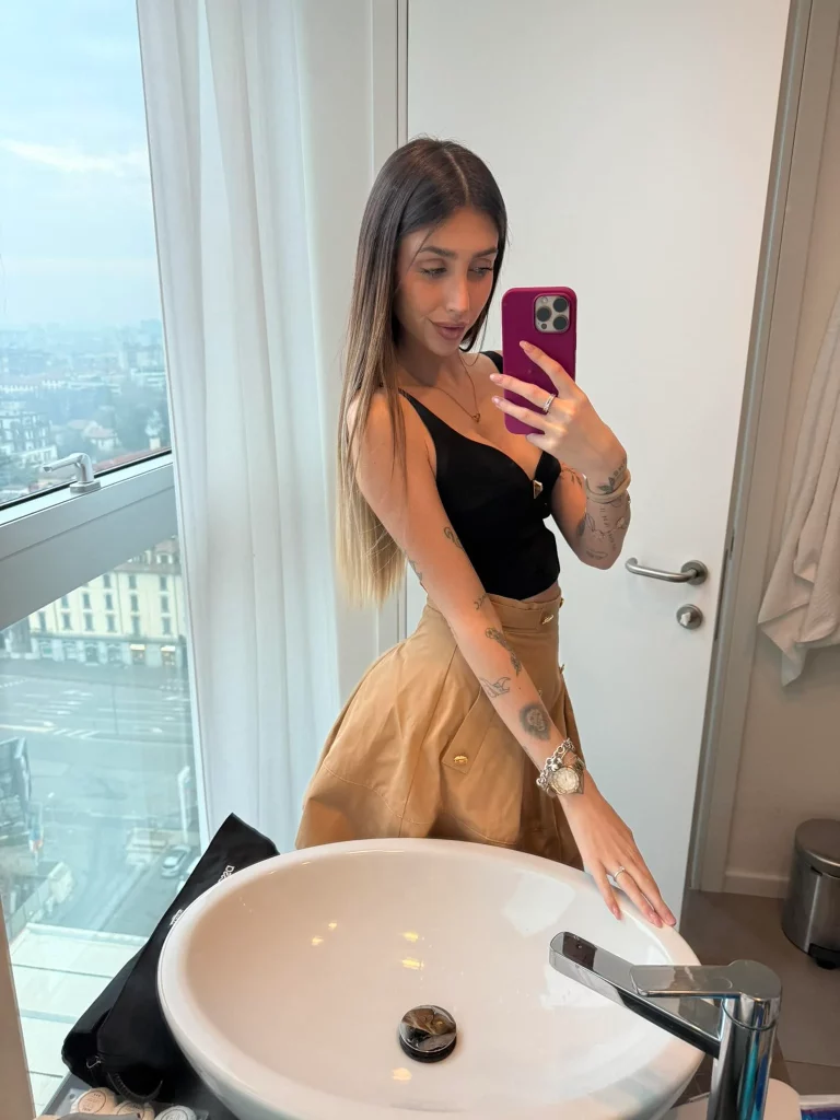 Michelle Comi, modella di OnlyFans, foto in bagno con un top nero aderente.