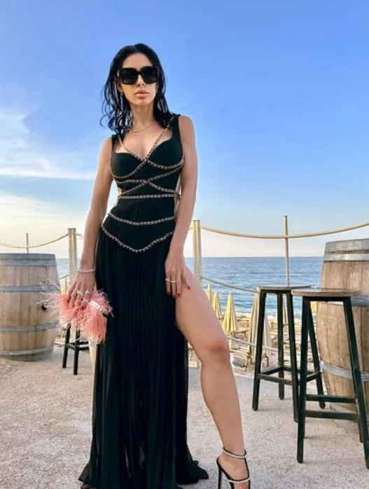 Virginia Olivero, modella OnlyFans, in piedi in un elegante e sexy vestito nero.