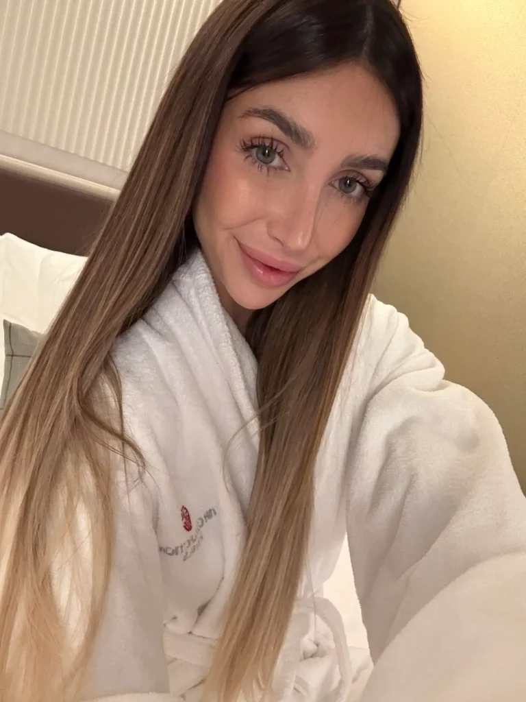 Michelle Comi, modella di OnlyFans, selfie in camera da letto con accappatoio.