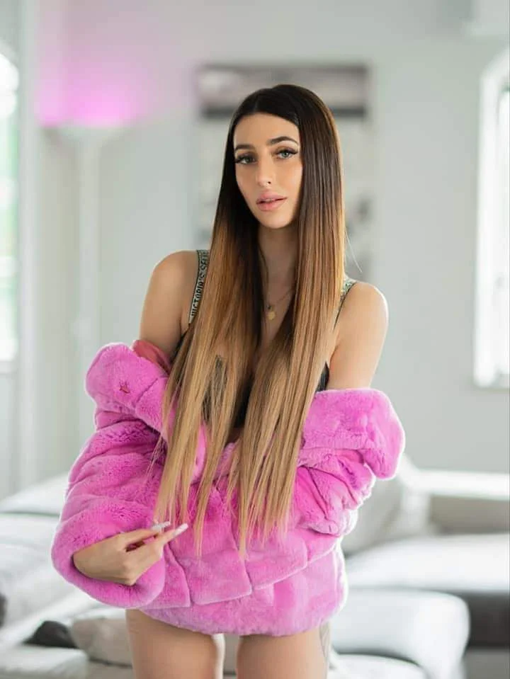 Michelle Comi, modella di OnlyFans, foto con un cardigan rosa peloso.