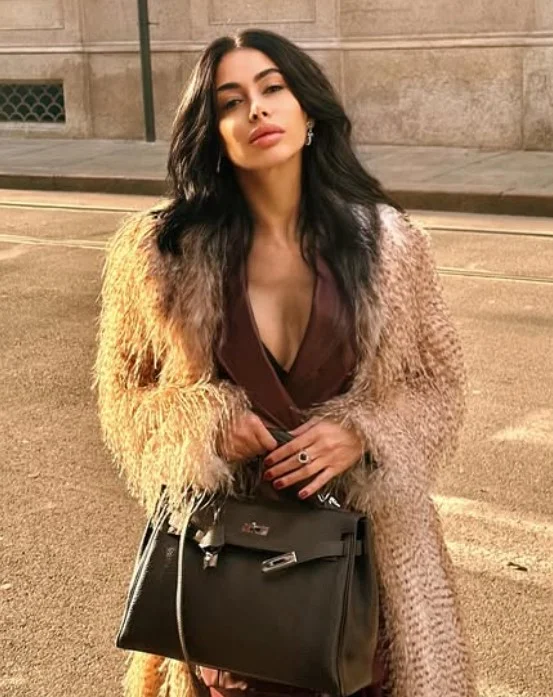 Virginia Olivero, modella OnlyFans, in piedi con un vestito marrone sexy.