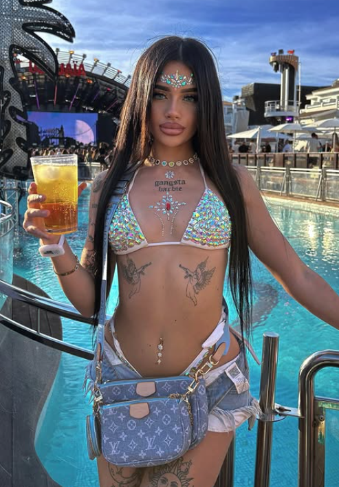 Vittoria Lazzari accanto a una piscina con indosso un reggiseno blu sexy e pantaloncini di jeans