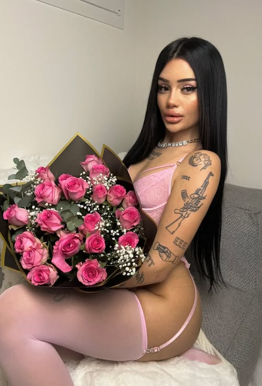 Vittoria Lazzari indossa un sexy abito rosa mentre tiene in mano un mazzo di fiori