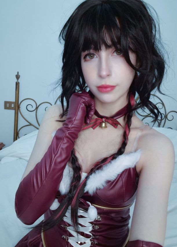 LolliGaia indossa un sexy costume da cosplay color bordeaux ed è seduta sul suo letto