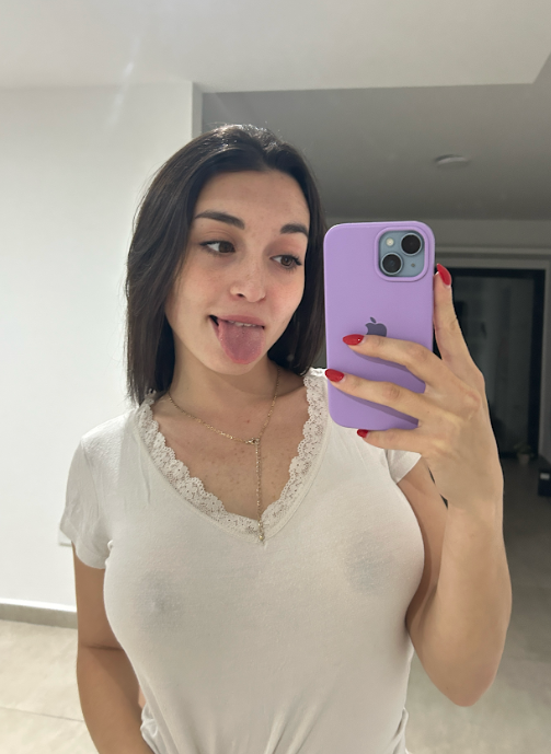 Maria Luna indossa un sexy top bianco mentre tiene in mano il telefono.